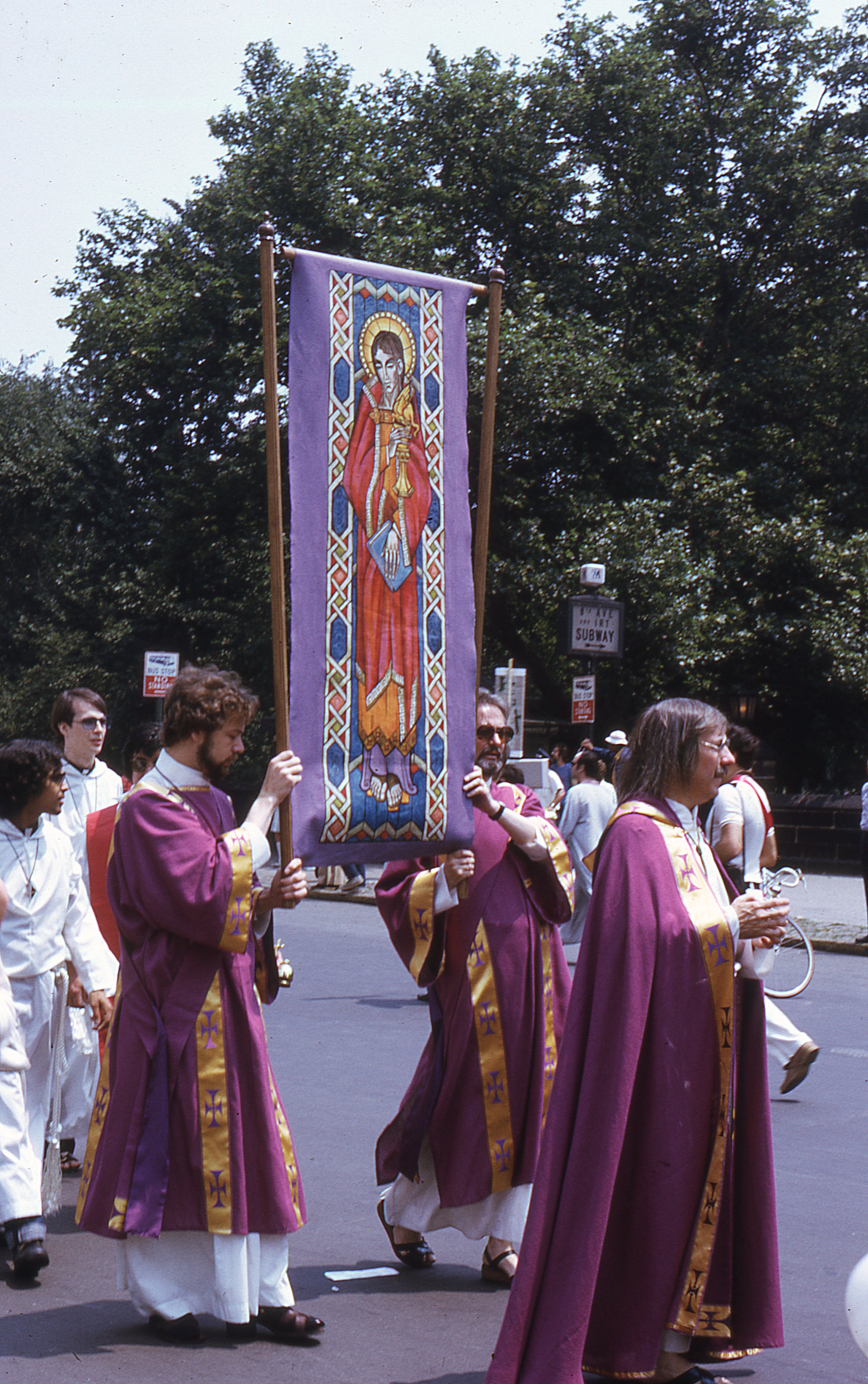 Fr. Robert Mary Clement leads members of the Church of the Beloved Disciple during the Fourth Annual Christopher Street Liberation Day March and Rally on June 24, 1973. Flanking the processional banner of St. John the Beloved are John Darcy Noble (left) and Leo M. Joseph (right), who carry the banner through the streets of Manhattan. Clothed in liturgical vestments, the congregation offered a striking public witness that LGBTQ people belonged fully within the sacramental life of the Church.