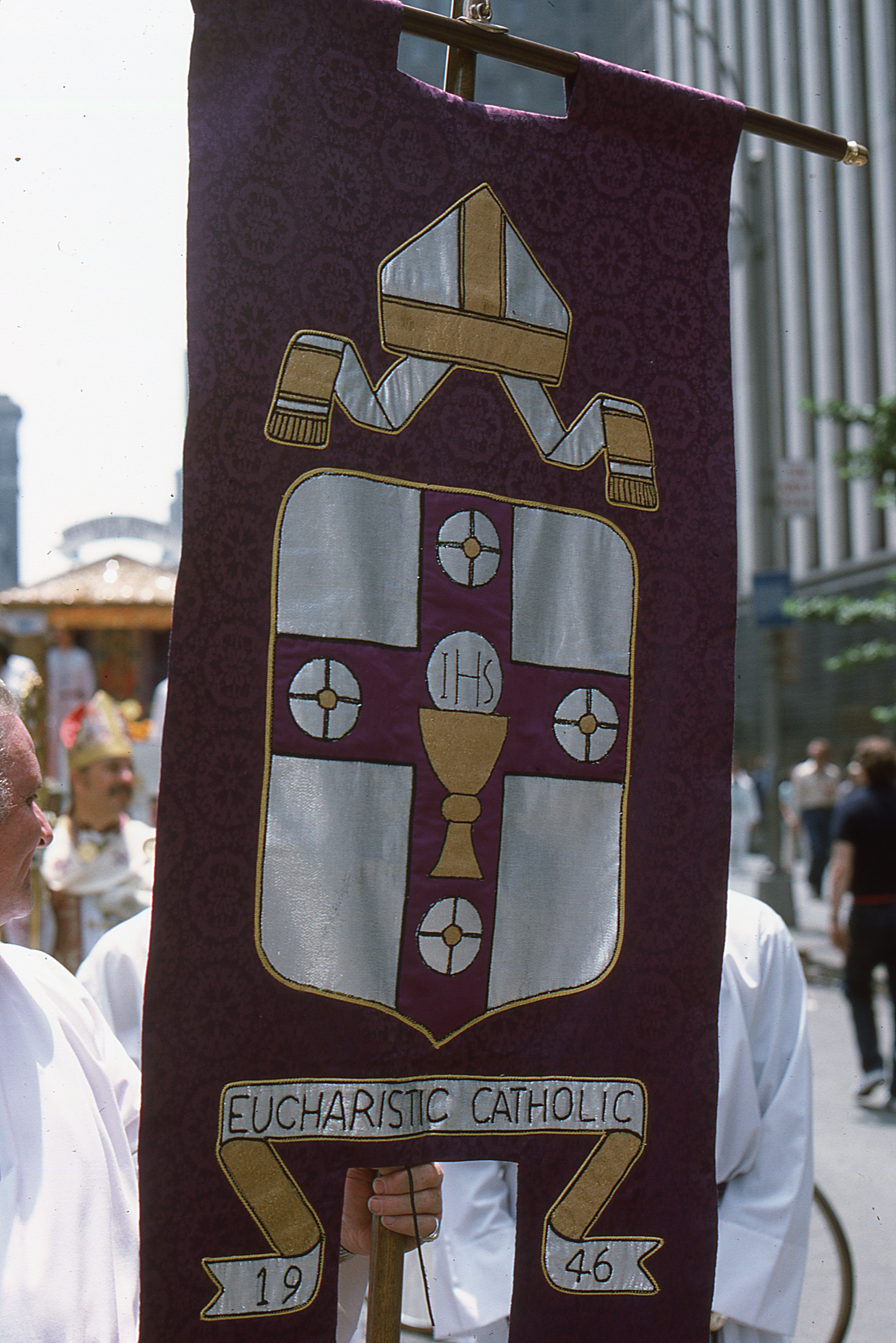 Carried by members of the Church of the Beloved Disciple during the Fifth Annual Christopher Street Liberation Day March on June 30, 1974, this processional banner features heraldic imagery created by the Church of the Beloved Disciple in honor of the Eucharistic Catholic Church, founded by Archbishop George Augustine Hyde in 1946. By designing and publicly displaying a coat of arms for the Eucharistic Catholic Church, the congregation affirmed its spiritual and historical continuity with Hyde's pioneering ministry. The banner proclaimed the Church of the Beloved Disciple's understanding of itself as the successor to the Eucharistic Catholic Church, continuing its mission of providing a sacramental home for LGBTQ Christians within the historic Catholic tradition.