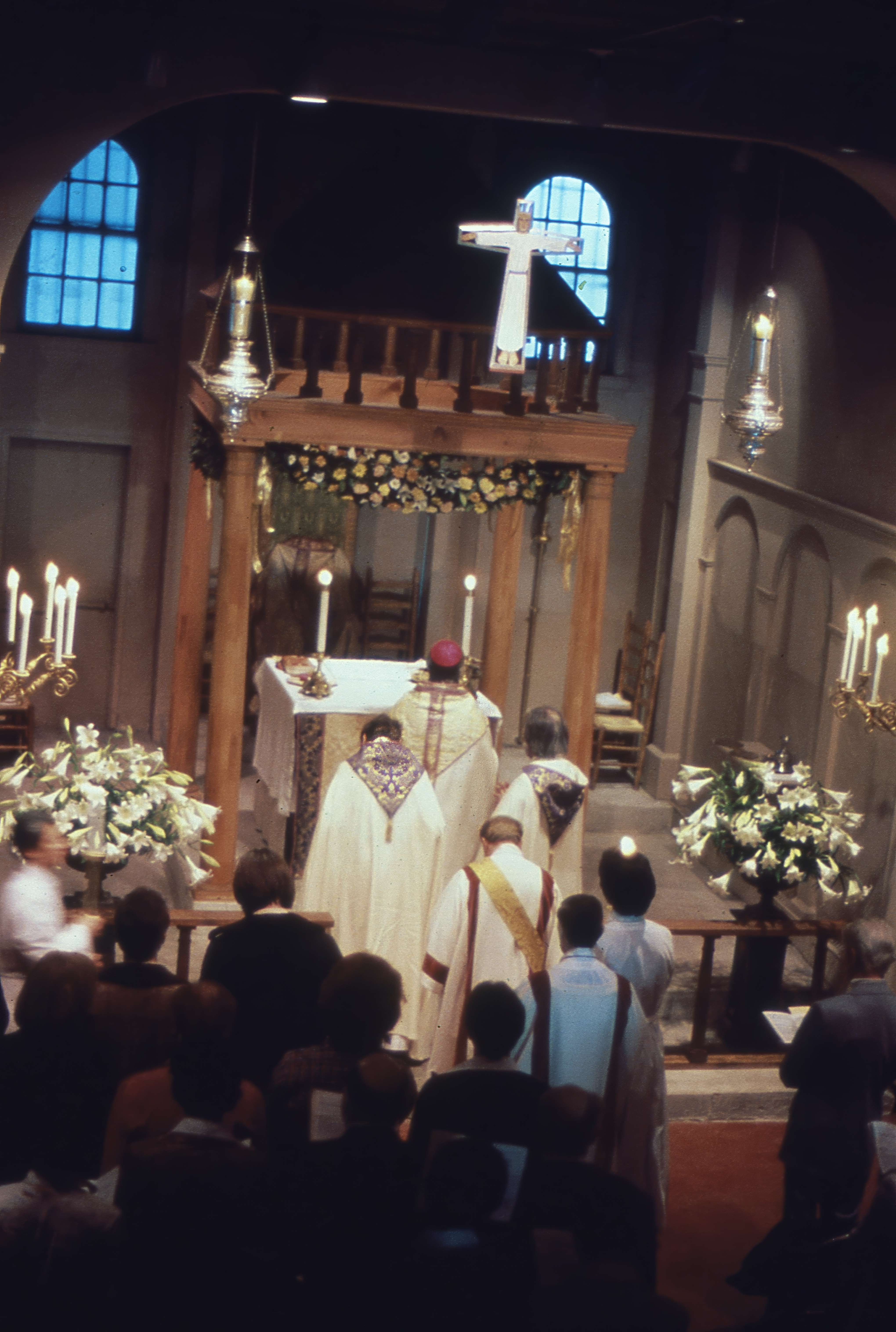 Viewed from the rear of the sanctuary, Archbishop Robert M. Clement processes to the altar with Fr. Leo (on his left) and Fr. John (on his right) before celebrating the Pontifical Mass of Easter Sunday before a congregation filling the Church of the Beloved Disciple at 348 West 14th Street. The elevated altar, adorned with lilies, candles, and a suspended crucifix, provided a setting for one of the most solemn liturgies of the Christian year, celebrated according to the ceremonial traditions of the Catholic Church. This image captures the church at the height of its liturgical life, when its permanent home had become both a place of worship and a refuge for LGBTQ Christians seeking a sacramental community.