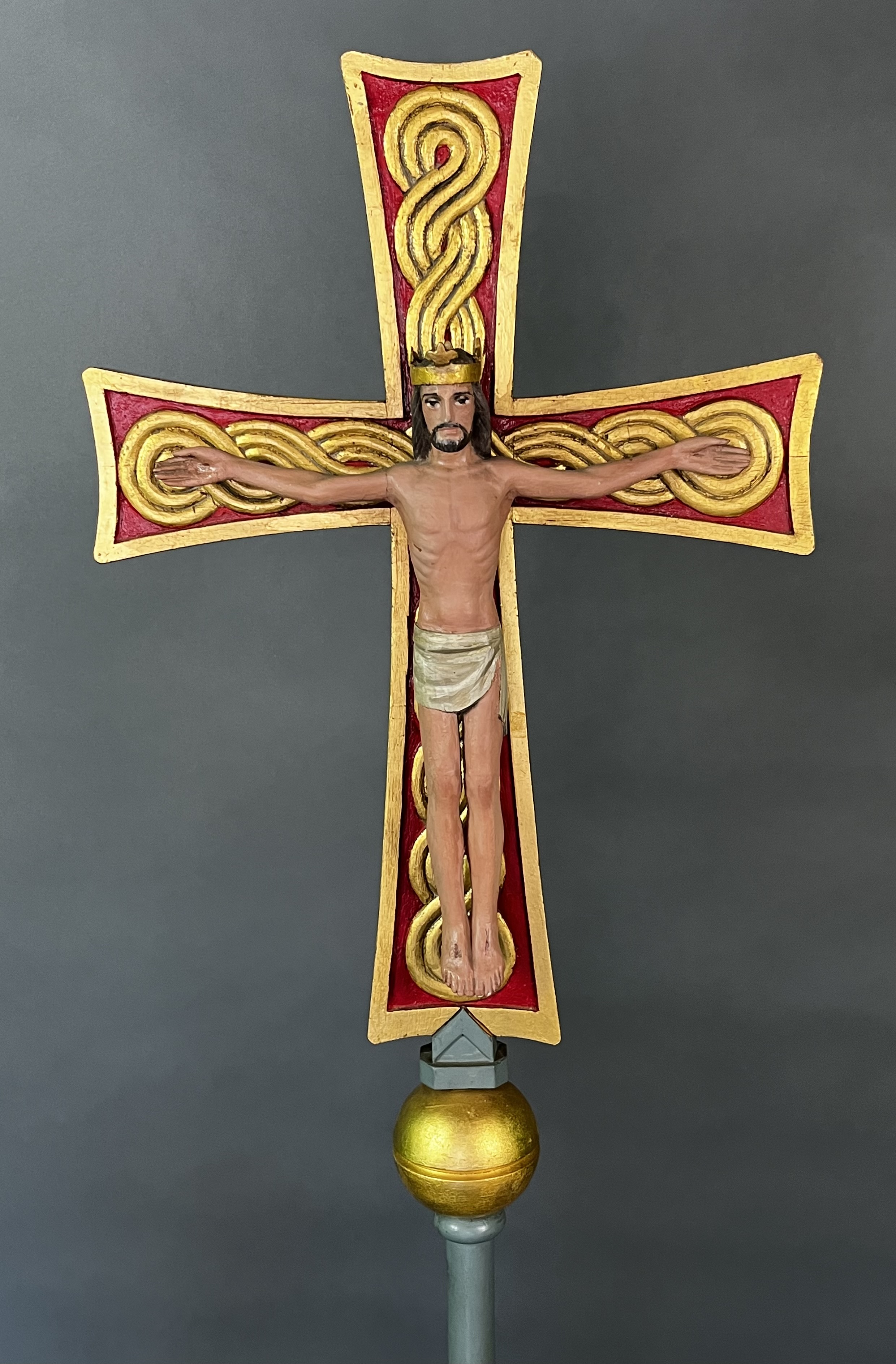 Carved by the noted ecclesiastical sculptor Robert ("Robbie") Robbins, this processional crucifix was commissioned for the Church of the Beloved Disciple and served as one of the principal symbols of the congregation's public and liturgical life. Carried in solemn liturgies, feast day processions, and in public marches, the cross reflects Robbins's distinctive synthesis of medieval and modern forms. Christ is depicted as the crucified King, crowned and reigning from the Tree of Life, while the interlaced Celtic ornament that fills the cross evokes the eternal and unbroken life of God. Robbins, whose work adorned numerous Roman Catholic and Anglo-Catholic churches along the East Coast, created this crucifix specifically for the Church of the Beloved Disciple.