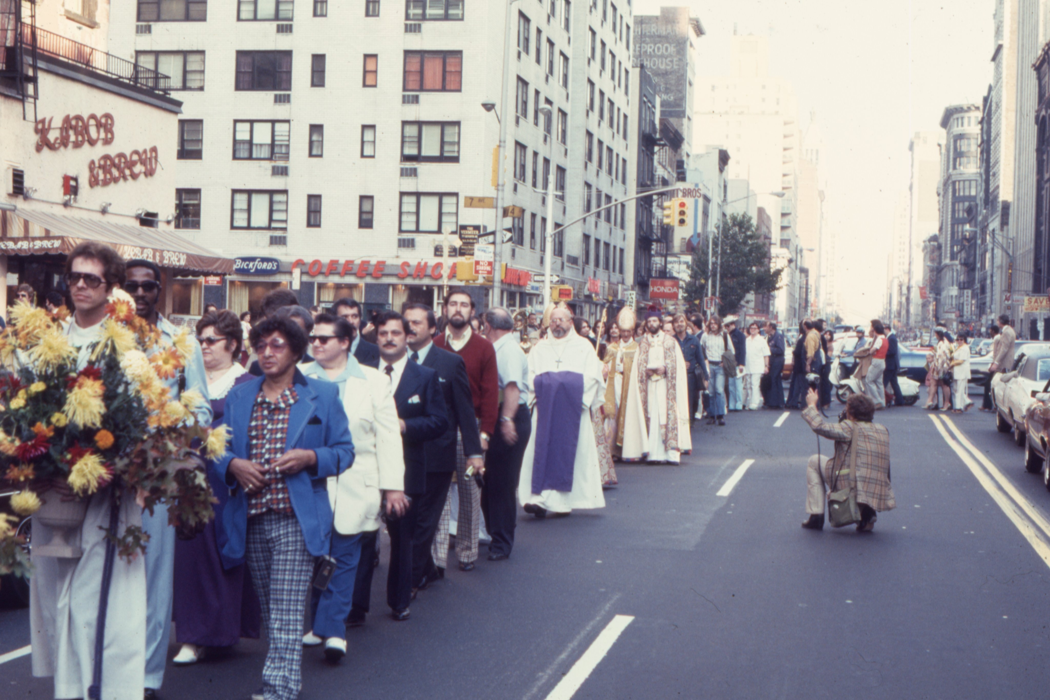 Members of the congregation, clergy, and supporters follow behind the bishops as the procession makes its way from Metropolitan-Duane United Methodist Church to the Church of the Beloved Disciple after Bishop Clement's consecration. Led by processional crosses, flowers, and banners, the gathering transformed the streets of Greenwich Village into an extension of the liturgy, expressing the Church of the Beloved Disciple's conviction that sacramental life belonged not only within church walls but also in the public witness of a community claiming its place in both the Church and the city.